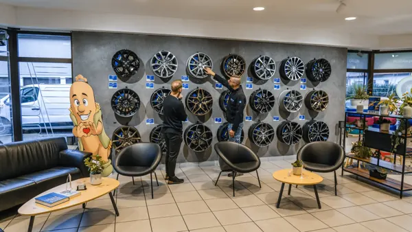 Two employees in front of a wall of alloy wheels in the showroom