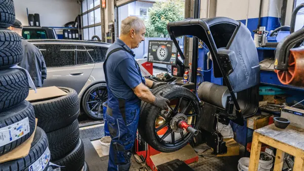 Mechaniker spannt ein Rad in die Wuchtmaschine